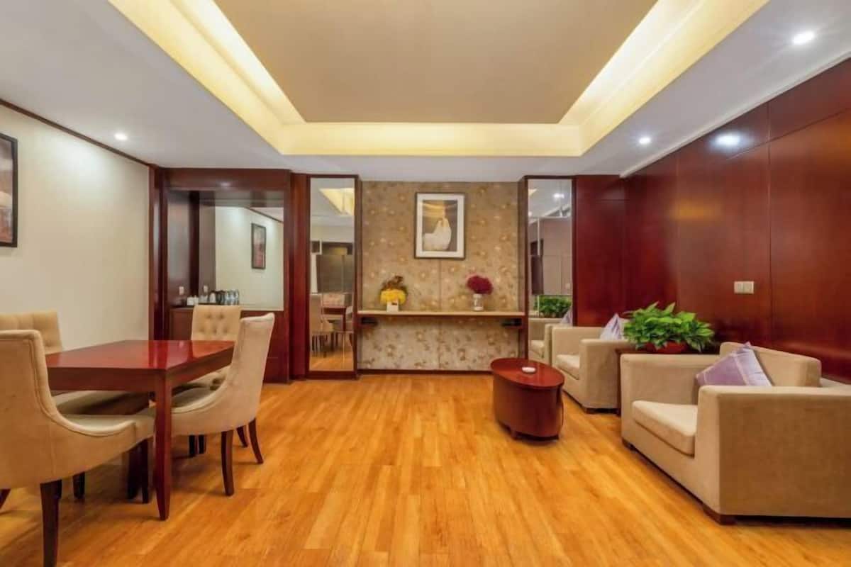 A spacious living area with a wooden floor, a dining table with chairs, a sofa set, and a small coffee table.