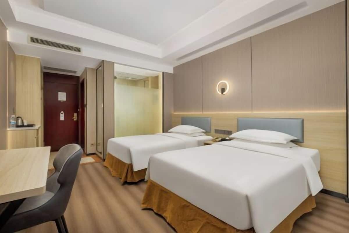 A hotel room with two beds, a desk, and a chair.