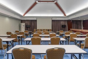A conference room with rows of tables and chairs, a projection screen, and a speaker system. - Halcyon Hotel & Resort (Yingtan)