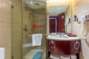 Un baño moderno con cabina de ducha de vidrio, tocador con lavabo y espejo.