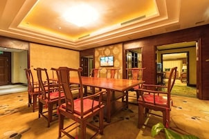 A conference room with a long table and chairs, a television screen, and a carpeted floor.