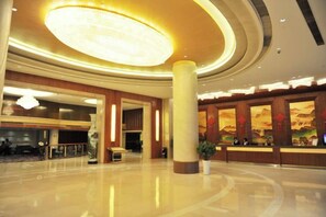 Un'ampia hall con un grande lampadario circolare, una reception e un'area salotto.
