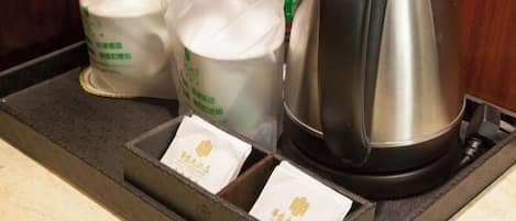 Una encimera de cocina con una tetera, dos botellas de leche y dos sobres de té.
