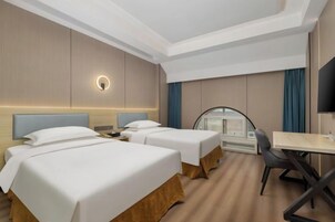 Una habitación de hotel con dos camas, un escritorio y una televisión.