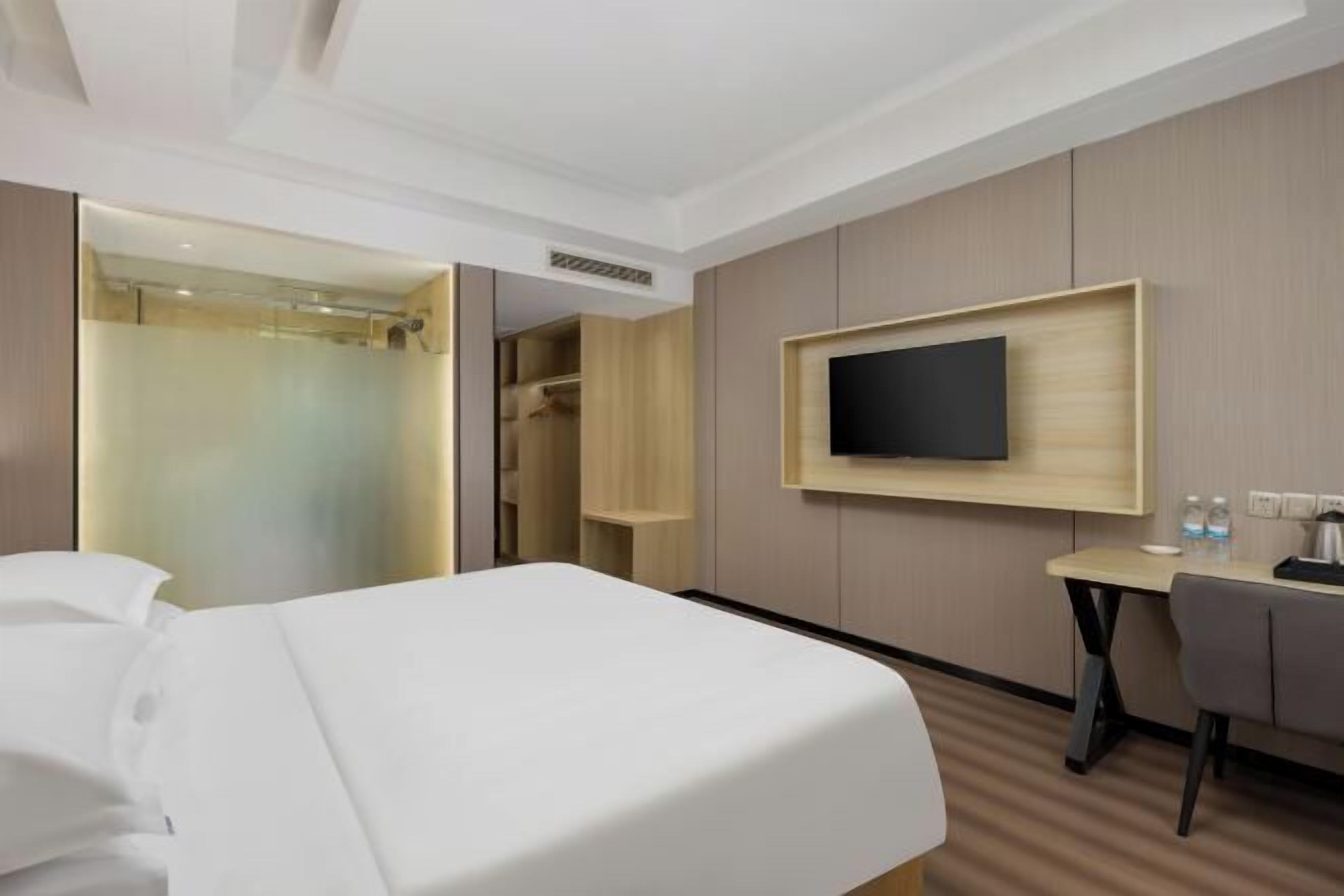 A hotel room with a bed, a desk, a TV, and a walk-in closet.