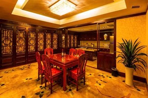 Un comedor con mesa y sillas de madera, una araña y una planta en maceta.
