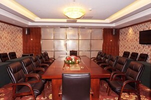 Une salle de conférence avec une longue table, des fauteuils en cuir, un lustre et une moquette à motifs.