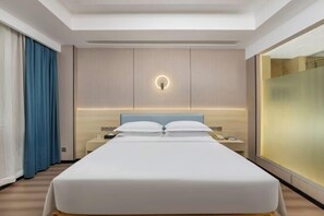 A modern hotel room with a large bed, a bedside table, a nightstand, a wall-mounted light, and a large window with curtains.