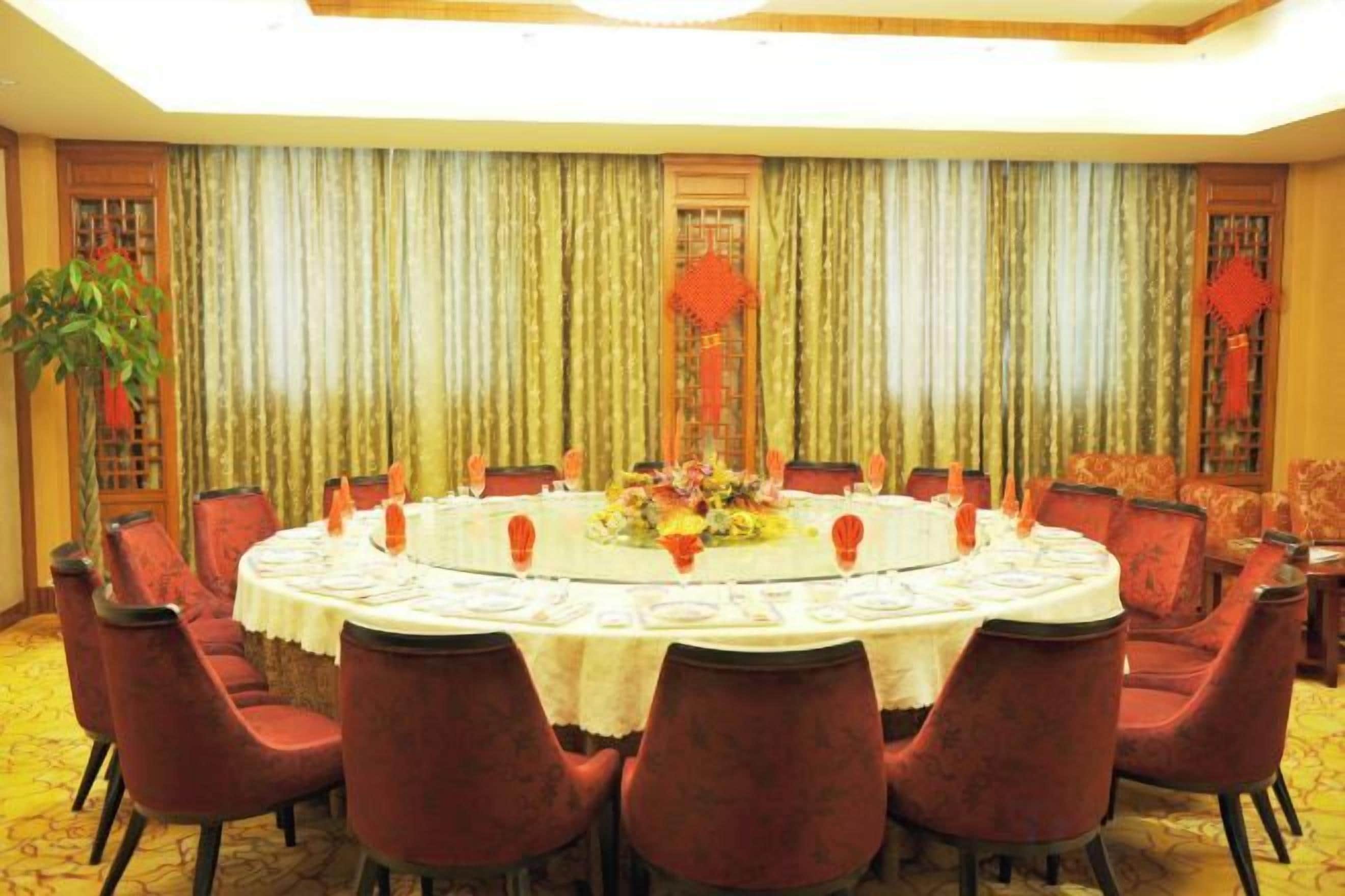 Une salle de conférence avec une table ronde, des chaises rouges et un arrangement floral au centre.