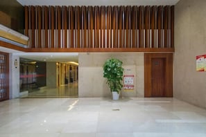 A lobby with a wooden slatted ceiling, a potted plant, a door, and a sign on the wall. - Halcyon Hotel & Resort (Yingtan)