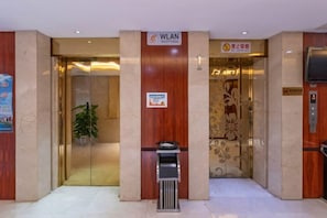 A hotel entrance with a reception desk, a trash bin, and an elevator. - Halcyon Hotel & Resort (Yingtan)
