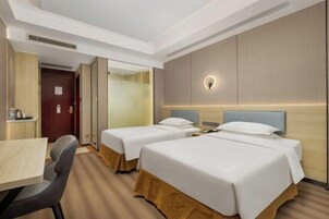 Habitación de hotel con dos camas, un escritorio y una silla.