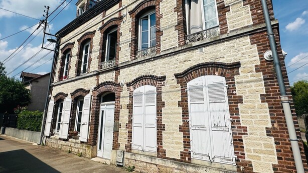 A two-story building with a brick facade and white shutters.
