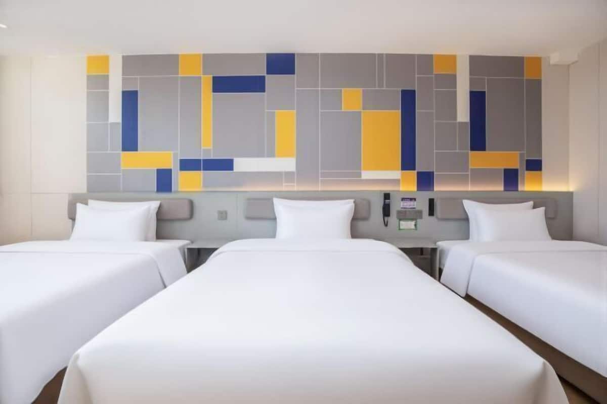 A hotel room with two beds, a modern wall art piece, and a bedside table with a phone and a lamp.