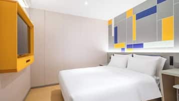 A modern hotel room with a large bed, a built-in TV, and a colorful abstract wall design.