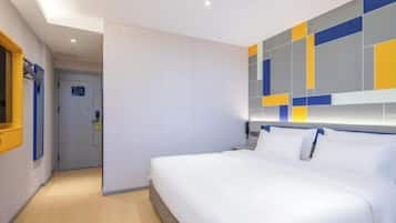 A hotel room with a large bed, a wall with geometric patterns, and a door in the background.