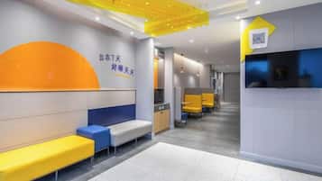 A modern hotel lobby with seating areas, a reception desk, and a QR code for digital services.