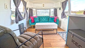 Un interior de autocaravana acogedor con un sofá azul turquesa, una mesita pequeña y un sofá de cuero.
