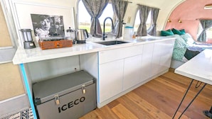Cocina compacta con alacenas blancas, un lavamanos y un refrigerador pequeño marcado ICECO.