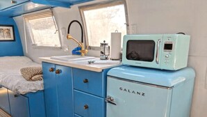 Eine kleine Küchenzeile mit einem blauen Galanz-Kühlschrank, einer Spüle und einer Mikrowelle.