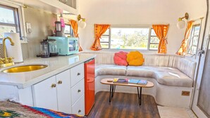 A compact living space with a kitchenette, a sofa, and a small table with books.