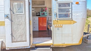 A vintage trailer with a kitchen area, including a refrigerator, microwave, and sink.