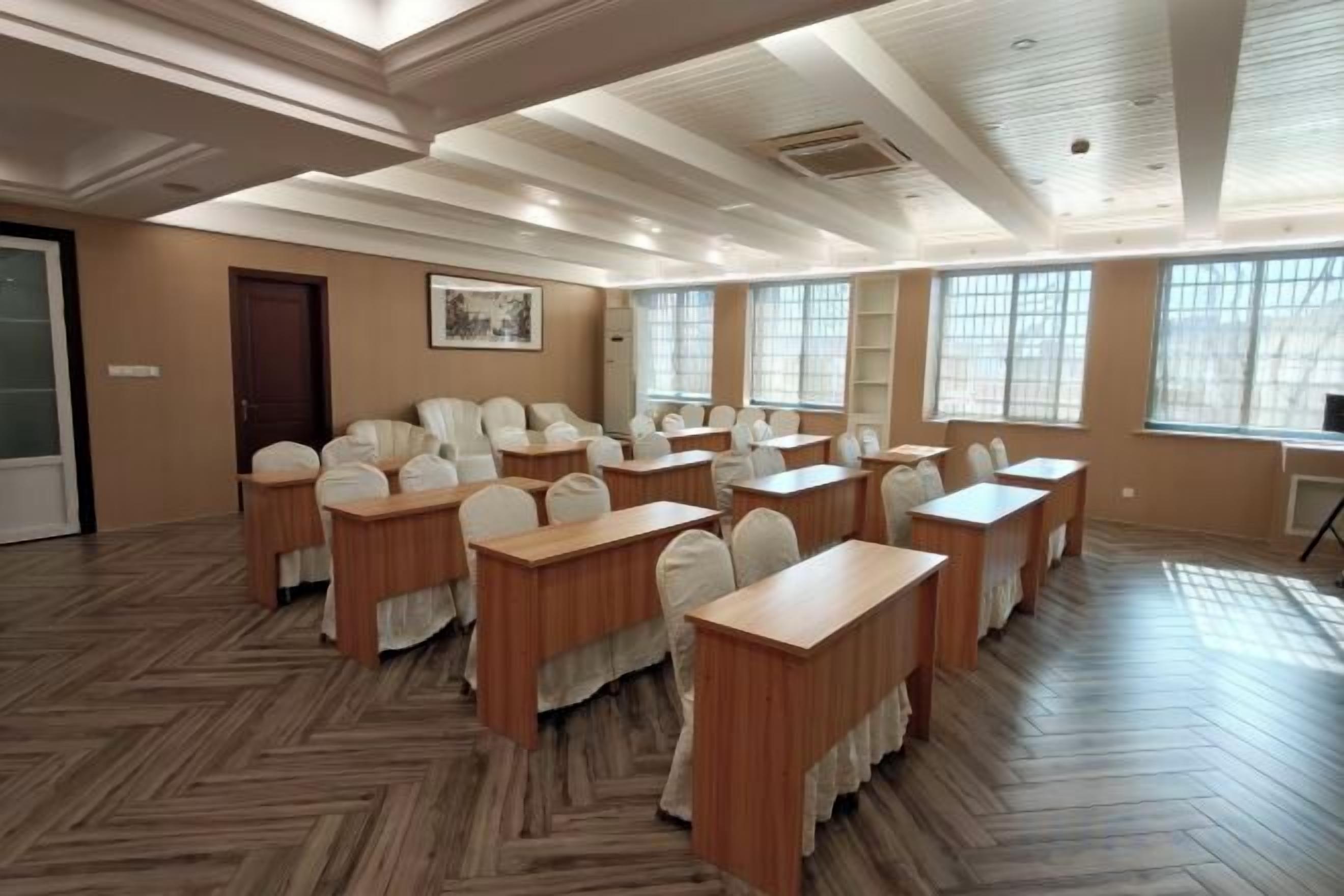 A conference room with multiple tables and chairs, large windows, and a wooden floor.