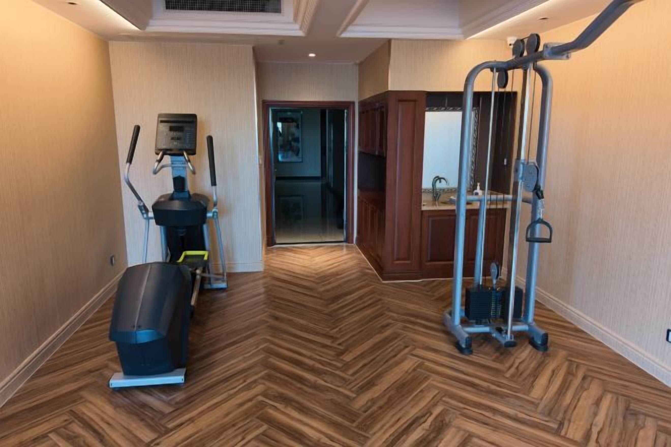 A hallway with a herringbone floor pattern, leading to a door.