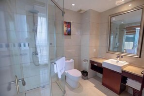 A modern bathroom with a glass shower enclosure, a white toilet, and a large mirror above the sink. - Gangxing Hotel (Zhuji)