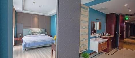 A modern hotel room with a bed, a bathroom with a sink and mirror, and a partition wall.