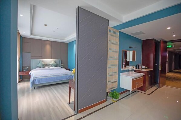 A modern hotel room with a bed, a bathroom with a sink and mirror, and a partition wall. - Gangxing Hotel (Zhuji)