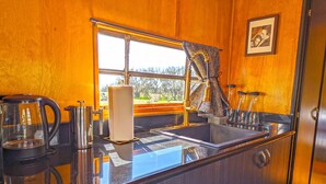 A kitchen with a sink, a coffee maker, and a window with curtains.