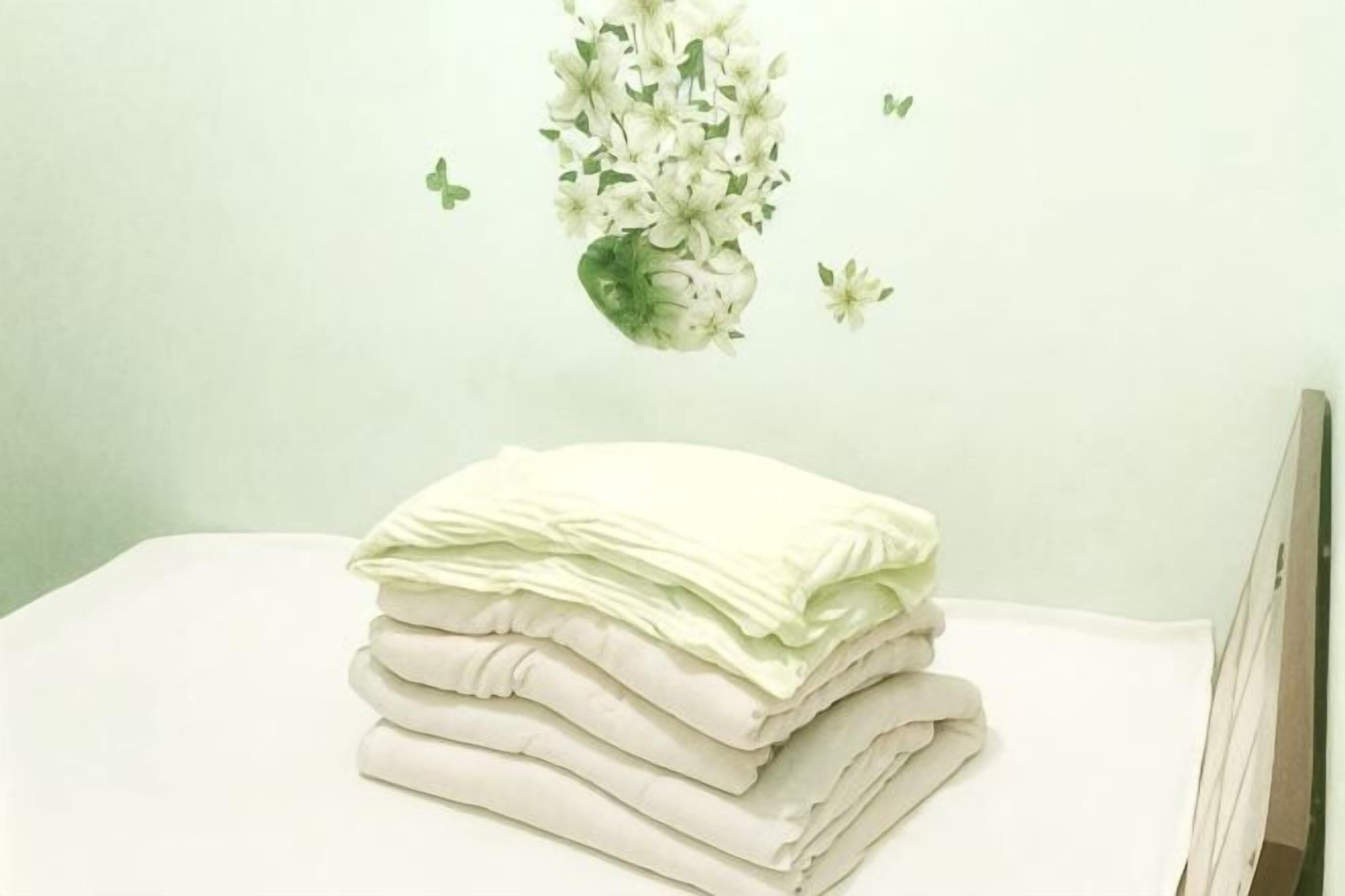 A neatly made bed with a stack of folded white blankets.