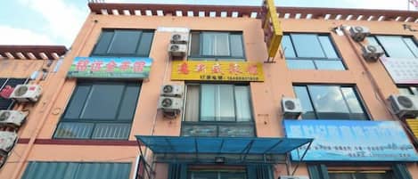 A multi-story building with commercial signage on the ground floor, air conditioning units on the exterior, and a covered entrance.