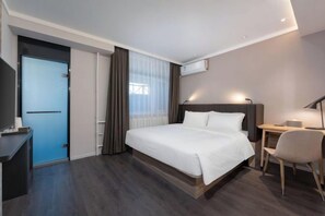 Ένα σύγχρονο δωμάτιο ξενοδοχείου με κρεβάτι, γραφείο, καρέκλα και κλιματιστικό.