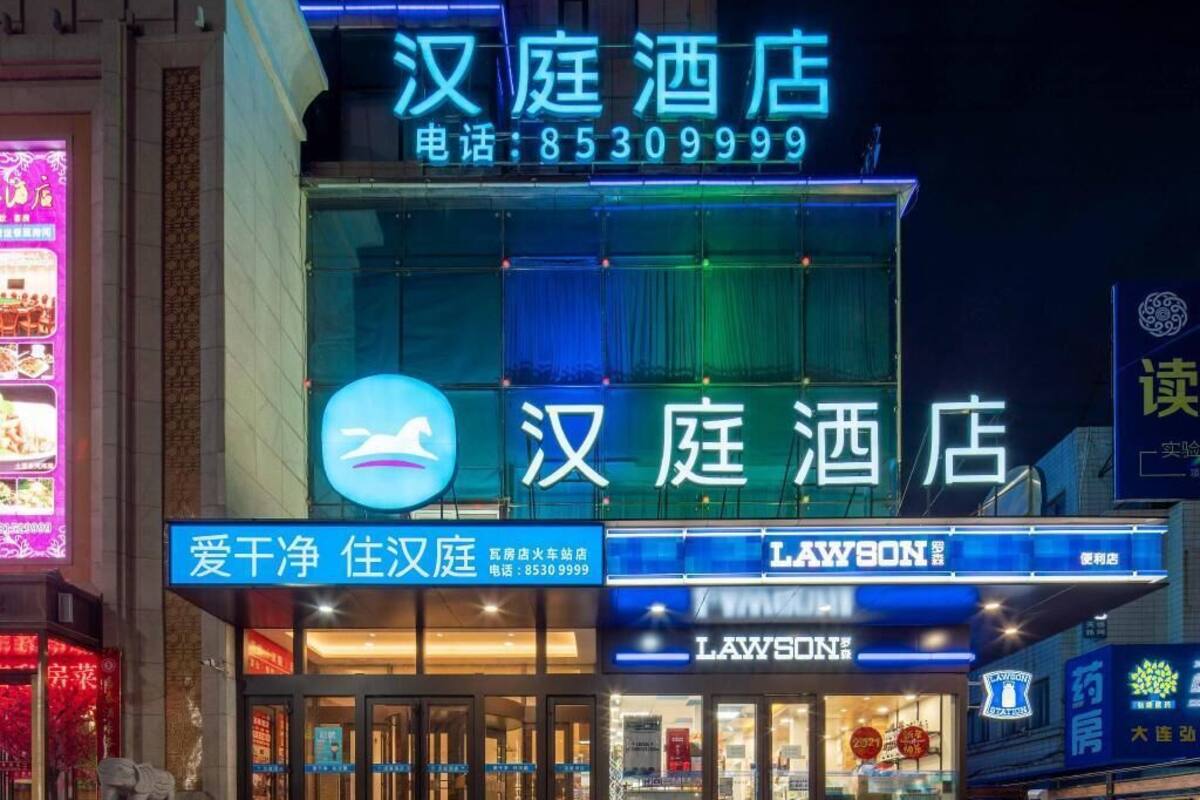 A hotel with a prominent sign, a Lawson store, and a statue outside.