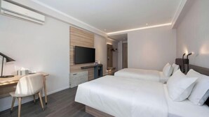 Et moderne hotelværelse med en stor seng, et skrivebord med stol, et fladskærms-tv og et indbygget klædeskab.
