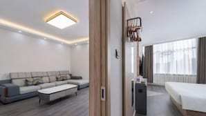 Et moderne hotelværelse med en sofa, en seng, et lille bord og et spejl.