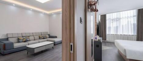 A modern hotel room with a sofa, a bed, a small table, and a mirror.