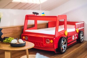 A red toy bed with wheels, a small table with a bowl of fruit, and a vase with flowers. - Kulangsu Fuxing Mansion (Sanqiutian Pier) (Xiamen)
