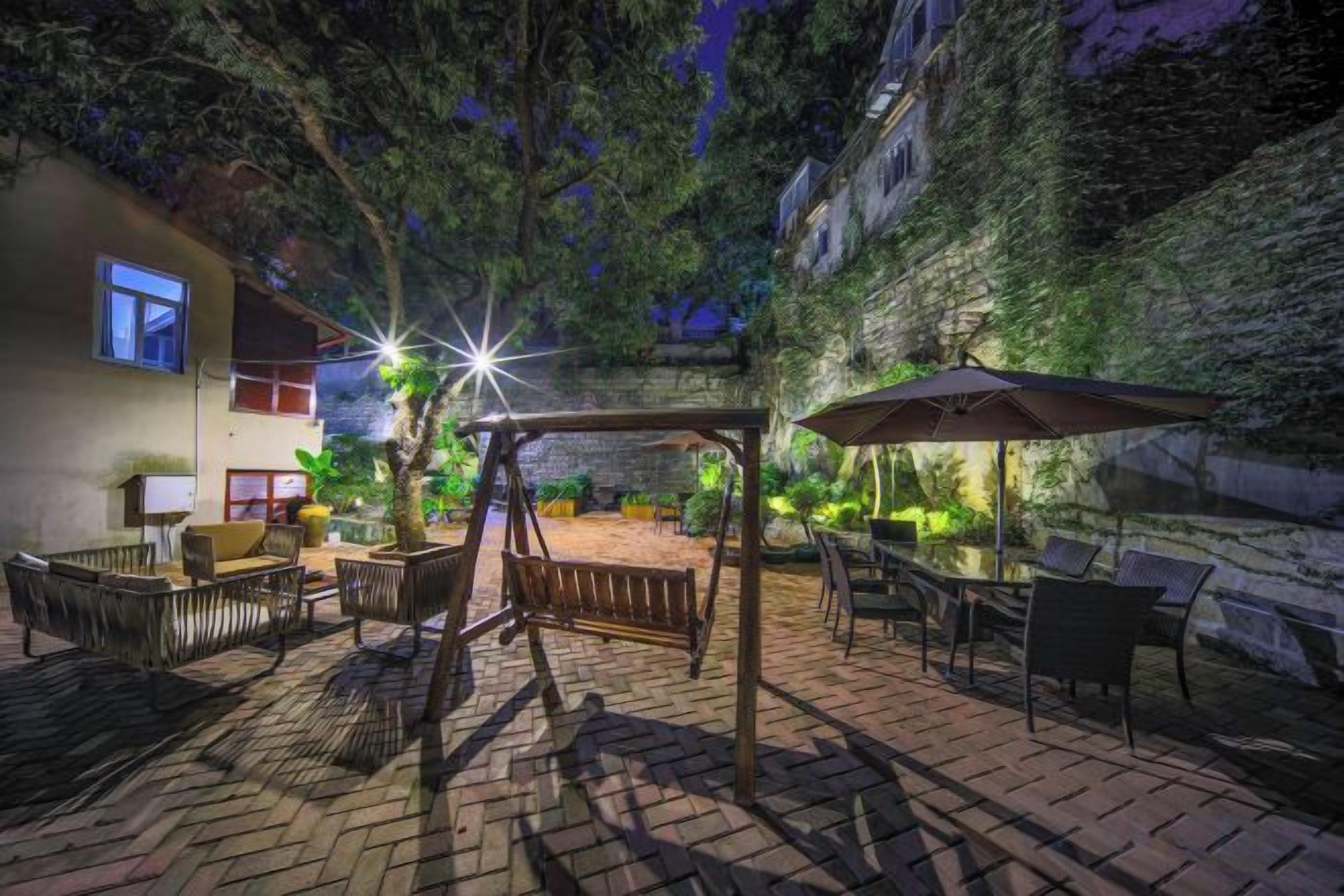 An outdoor patio area with a swing set, seating, and umbrellas.