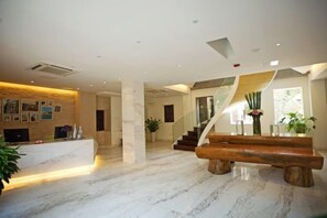 A spacious lobby with a marble floor, a reception desk, a staircase, and a large wooden bench. - Kulangsu Fuxing Mansion (Sanqiutian Pier) (Xiamen)
