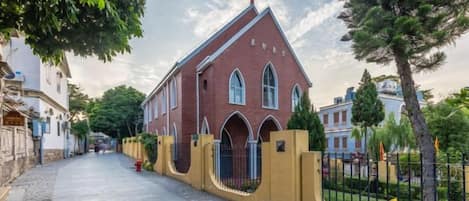 Una iglesia con fachada roja, ventanas de arco y una cruz en la parte superior.
