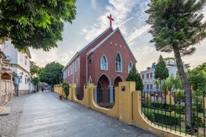 Una iglesia con fachada roja, ventanas de arco y una cruz en la parte superior.