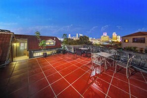 A rooftop terrace with red tiles, outdoor furniture, and a city skyline in the background. - Kulangsu Fuxing Mansion (Sanqiutian Pier) (Xiamen)