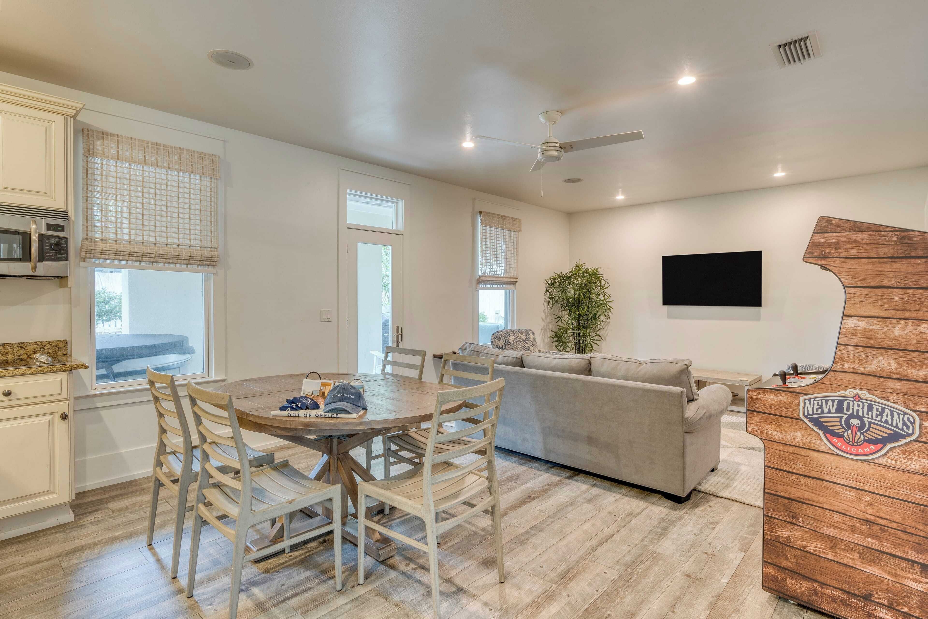 A modern kitchen with white cabinets, a dining table with chairs, a ceiling fan, and a wooden accent wall with a New Orleans logo.
