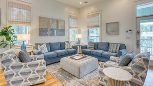 A modern living room with a grey and white patterned sofa set, a round ottoman, and a small round table. - Destin Dream by Avantstay 2-story Home, Walk to Beach (Miramar Beach)
