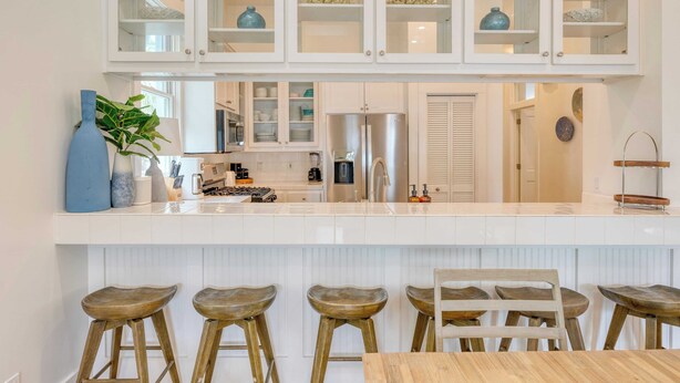 A modern kitchen with white cabinetry, a central island with stools, and a stainless steel refrigerator. - Destin Dream by Avantstay 2-story Home, Walk to Beach (Miramar Beach)