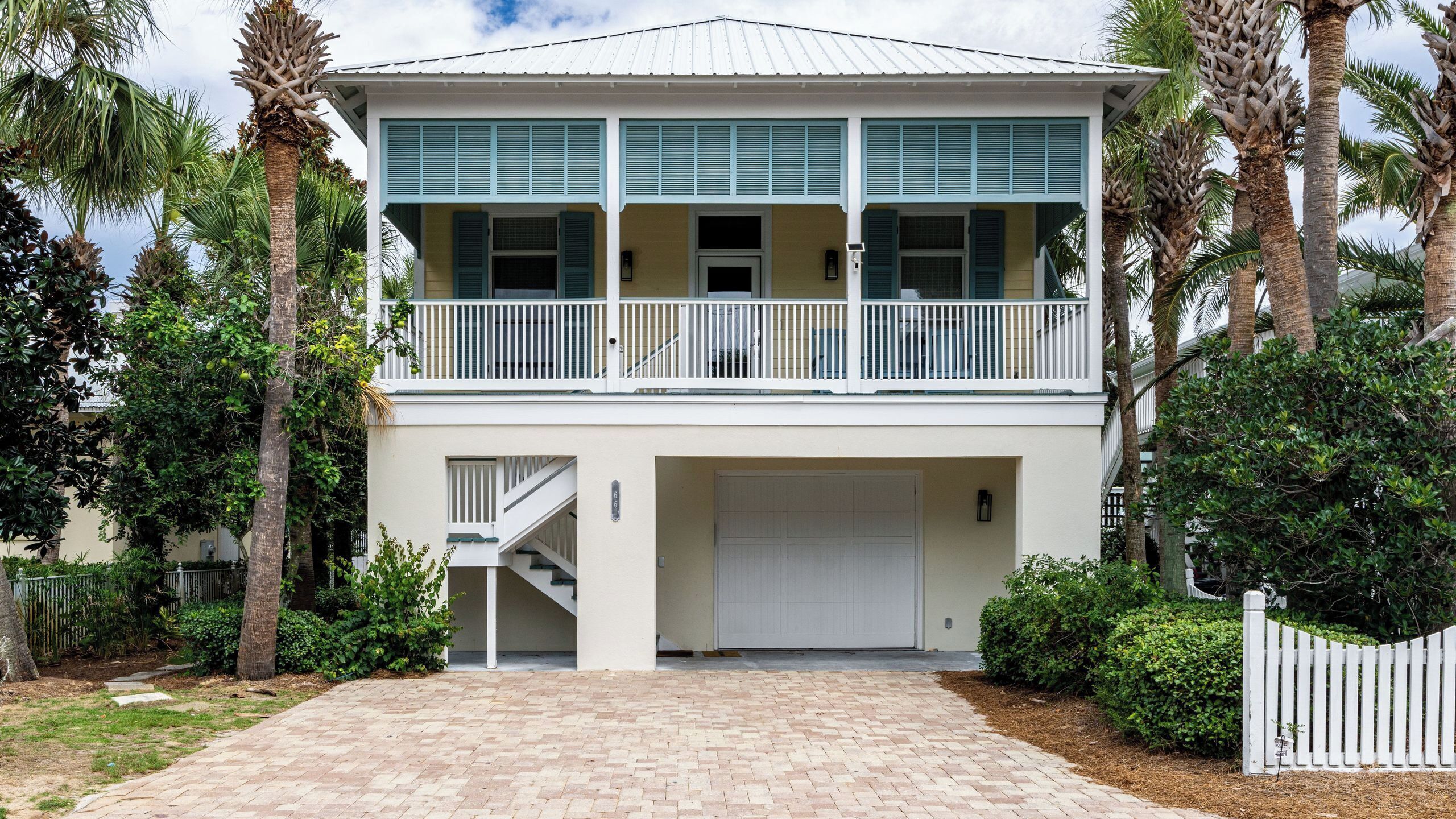 A two-story house with a balcony, a garage, and a brick driveway.