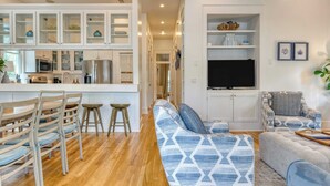 A modern kitchen with white cabinetry, a central island, and a dining area with wooden chairs and stools. - Destin Dream by Avantstay 2-story Home, Walk to Beach (Miramar Beach)